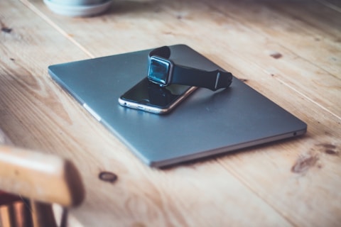 black Apple Watch on top of space gray iPhone 6