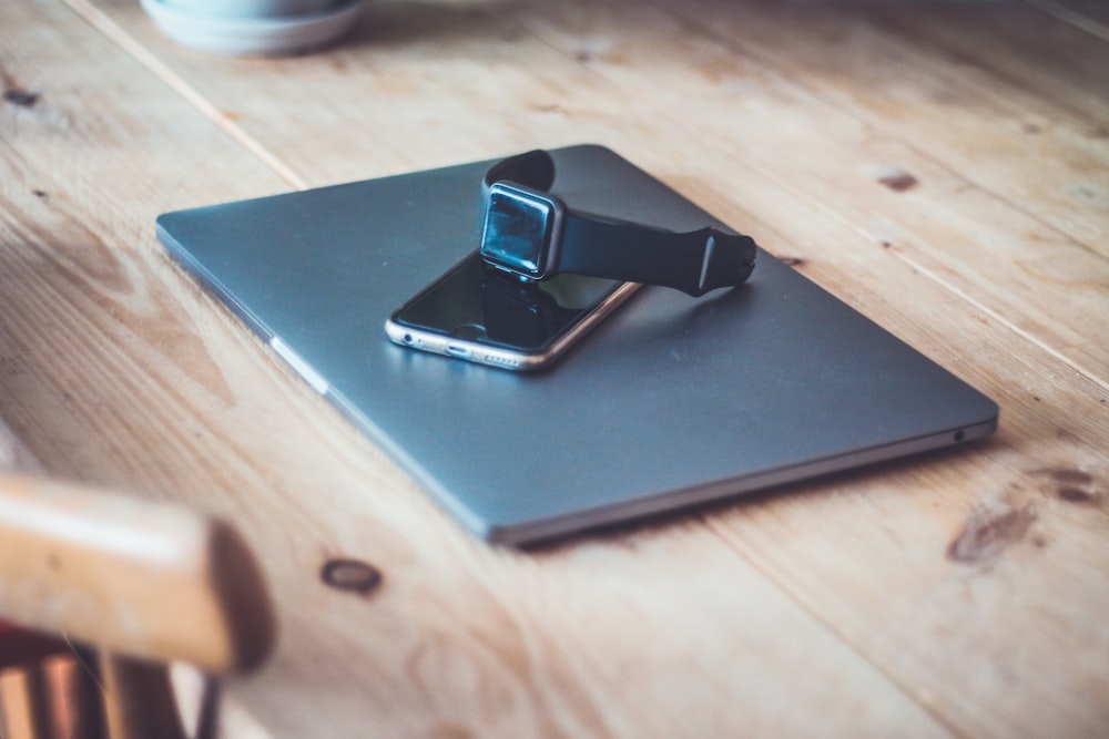 black Apple Watch on top of space gray iPhone 6