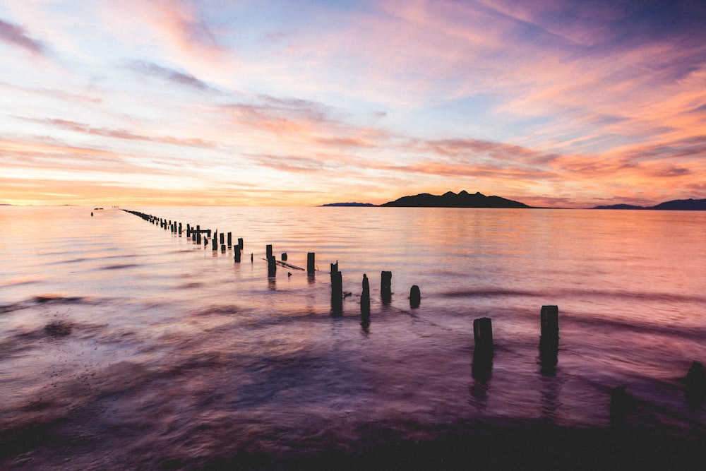 brown wooden dock base on body of water background of mountain