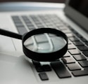 magnifying glass near gray laptop computer