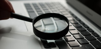 magnifying glass near gray laptop computer