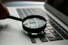 magnifying glass near gray laptop computer