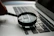 magnifying glass near gray laptop computer