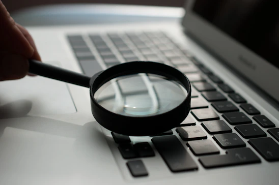 Close-up of a technician carefully inspecting a MacBook keyboard under bright, clean lighting.