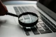 magnifying glass near gray laptop computer
