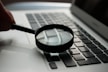magnifying glass near gray laptop computer