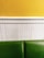 A minimalist interior wall design featuring a yellow upper section, a white beadboard midsection, and a green cushioned bench at the bottom.