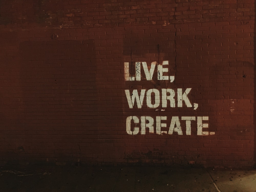 muro di mattoni rossi con vivere, lavorare, creare. citare