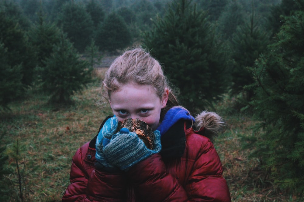 woman wearing red jacket covering her nose