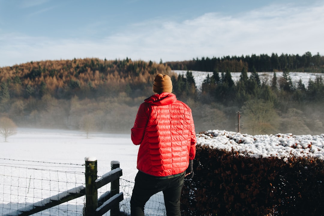 a person in a red jacket looking over a fence,