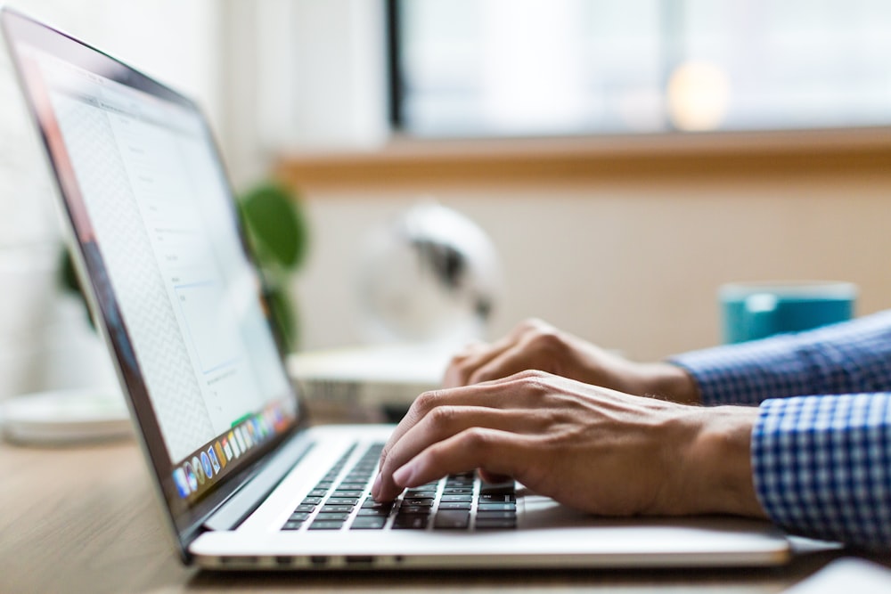 person typing on silver MacBook