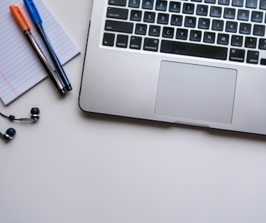 silver laptop computer beside white ruled paper