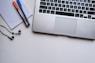 silver laptop computer beside white ruled paper