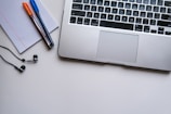 silver laptop computer beside white ruled paper