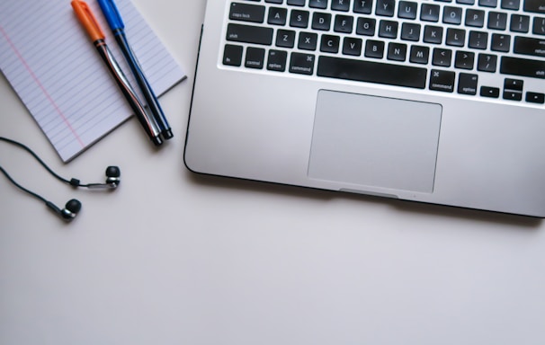 silver laptop computer beside white ruled paper