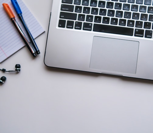 silver laptop computer beside white ruled paper