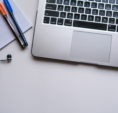 silver laptop computer beside white ruled paper