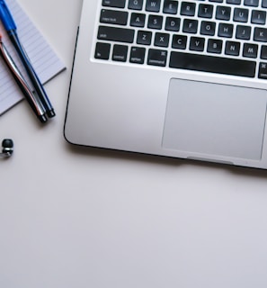 silver laptop computer beside white ruled paper