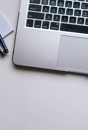 silver laptop computer beside white ruled paper