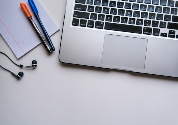 silver laptop computer beside white ruled paper