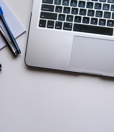 silver laptop computer beside white ruled paper