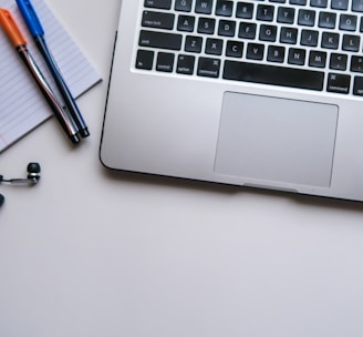 silver laptop computer beside white ruled paper