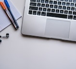 silver laptop computer beside white ruled paper