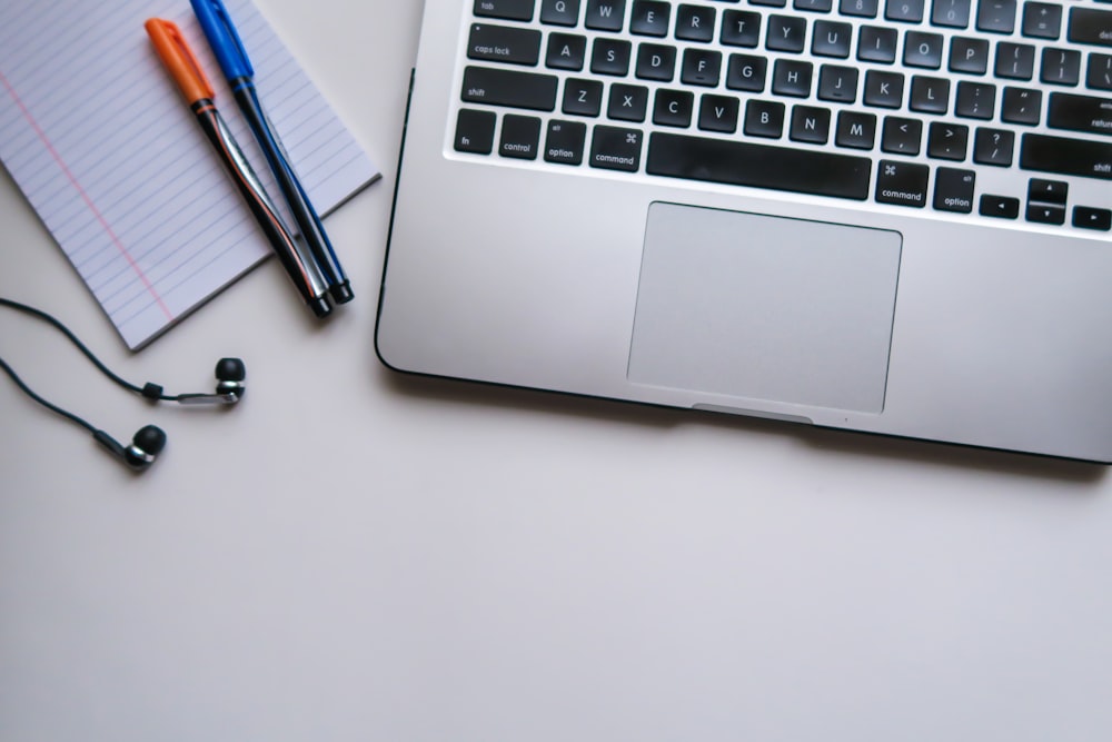 silver laptop computer beside white ruled paper