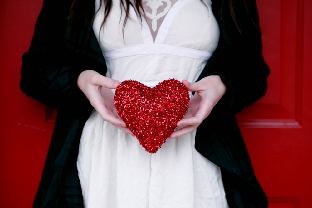 mujeres sosteniendo almohada de corazón rojo