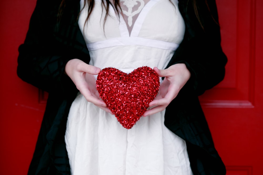 women holding red heart pillow