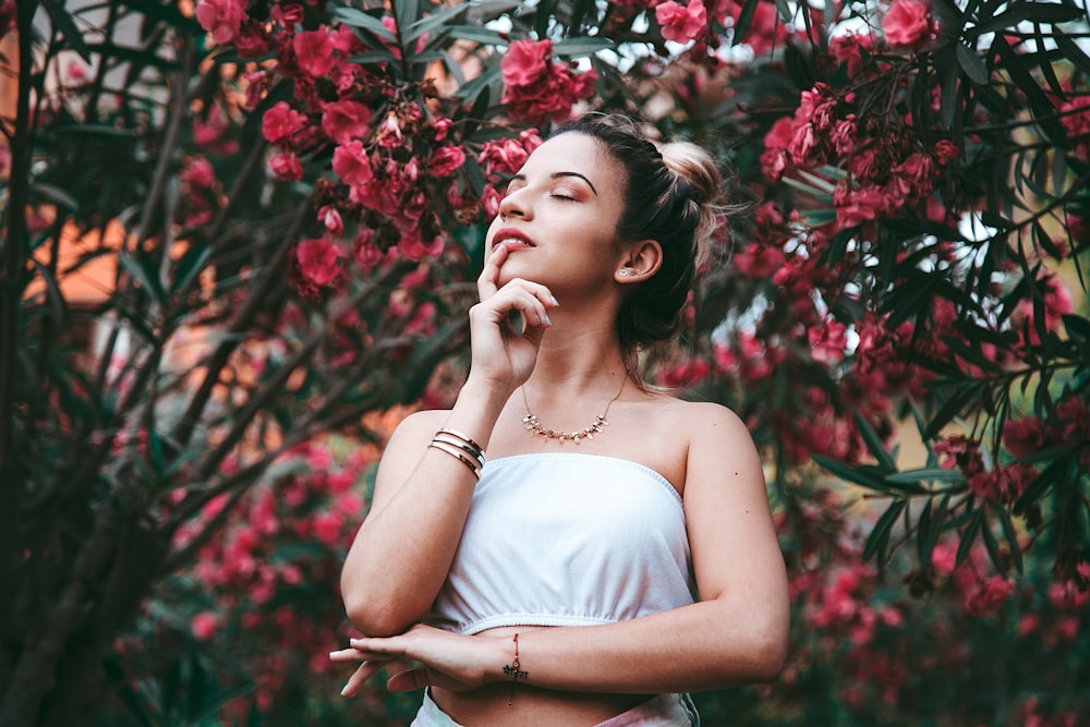 woman wearing tube top standing under flower during daytime