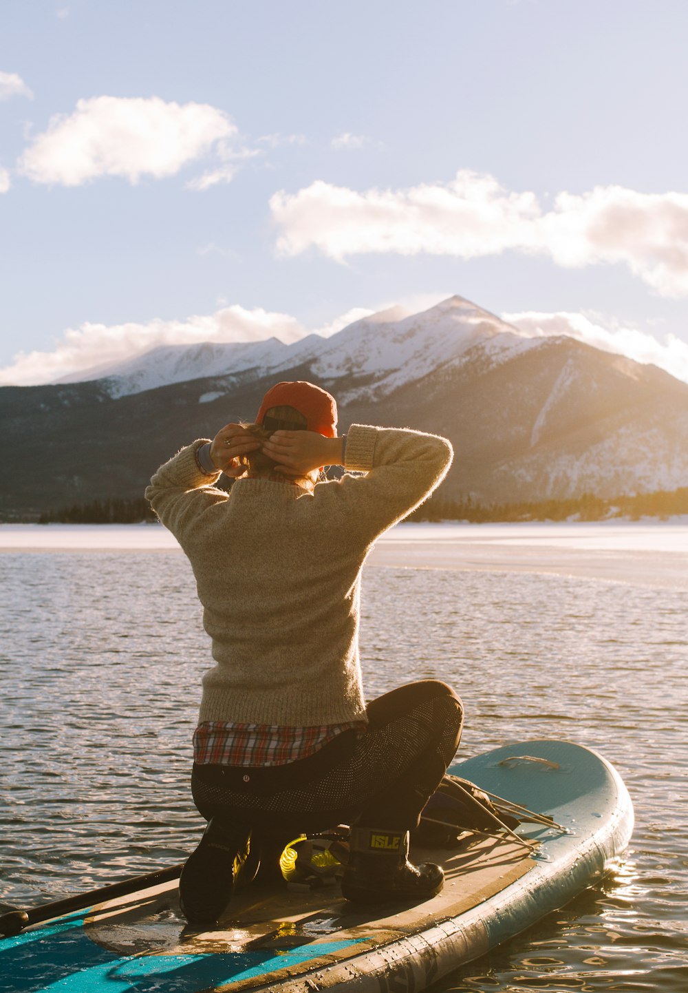 person riding waveboard on body of water near mountain at daytime