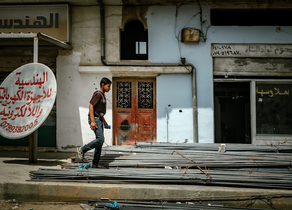 boy walking on metal frame beside building