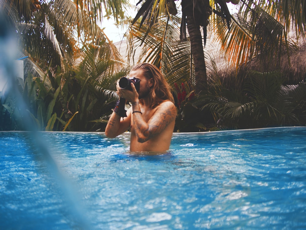 uomo che tiene la macchina fotografica in piscina