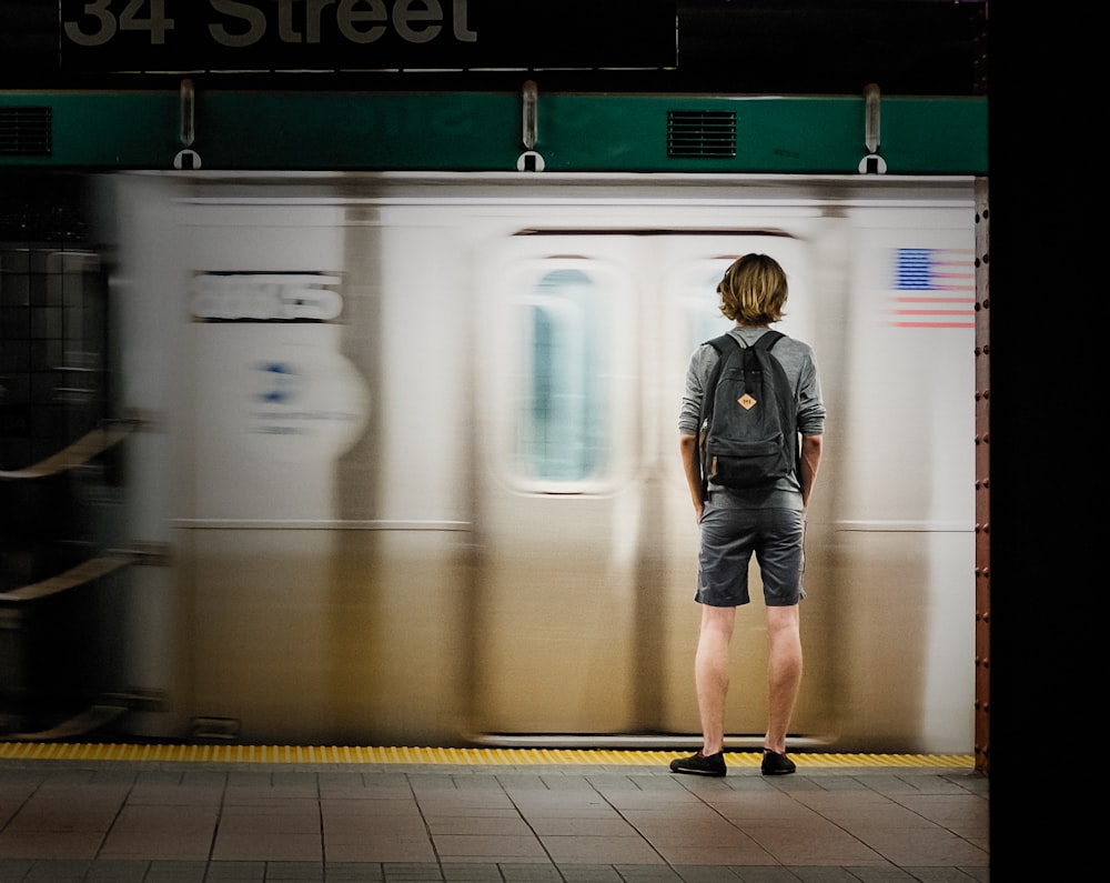 time lapse photography of man standing in front of train