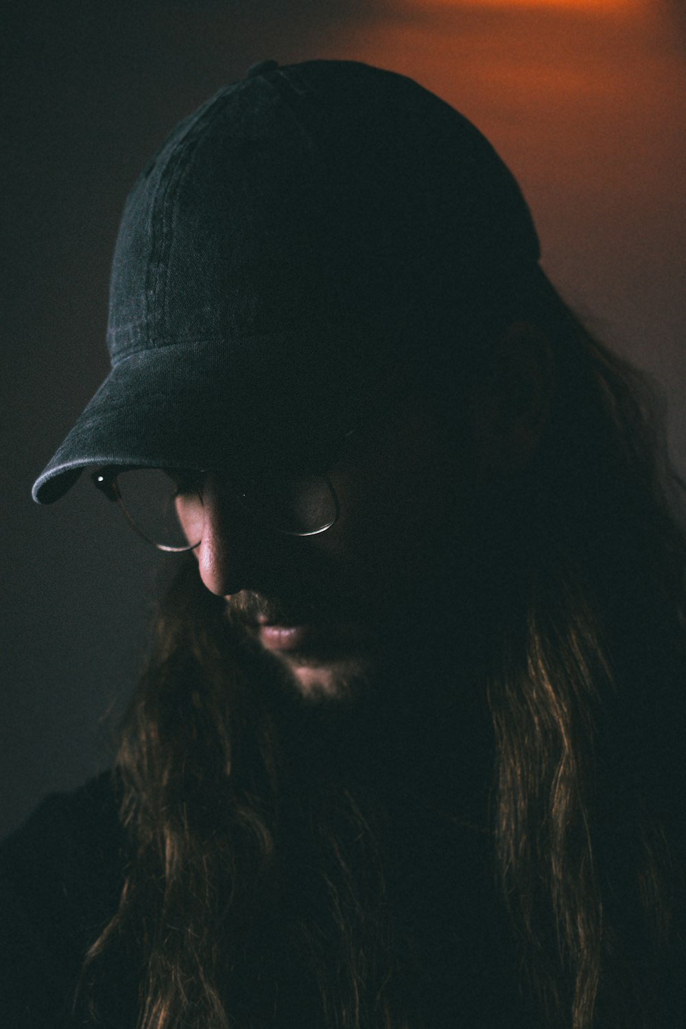 man wearing black fitted cap looking down closeup photography