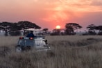 man riding on gray car during sunset