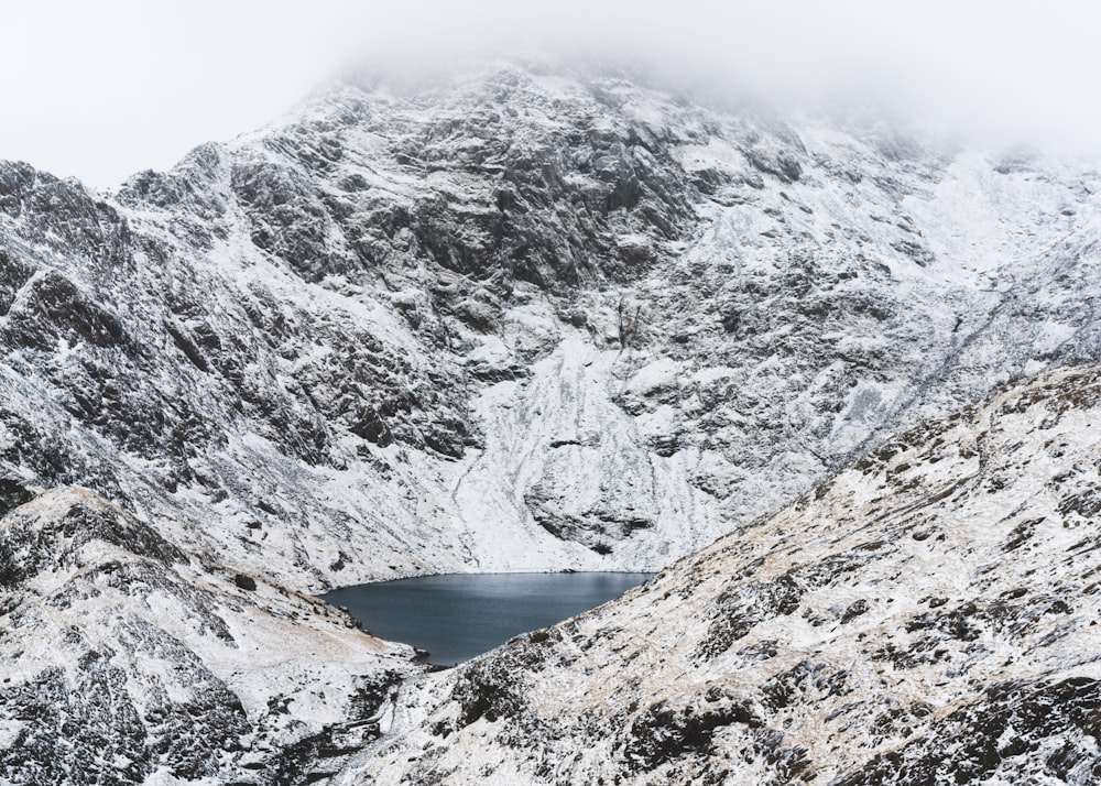 Plan d’eau calme entouré d’une montagne enneigée pendant la journée