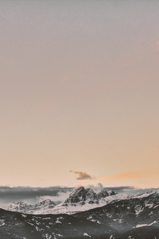 rock formation coated with snow under orange sky in Sass Putia Italy