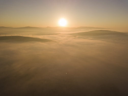 A panoramic shot of a wind farm at sunrise, blades gently turning against a golden sky.