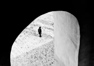 A minimalist still frame showing a solitary figure framed by architectural lines.
