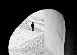 A minimalist still frame showing a solitary figure framed by architectural lines.