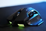 A sleek, black gaming mouse featuring a textured grip, multiple side buttons, and illuminated areas emitting green light. The mouse has a robust and ergonomic design, with a scroll wheel and other controls positioned for easy access.