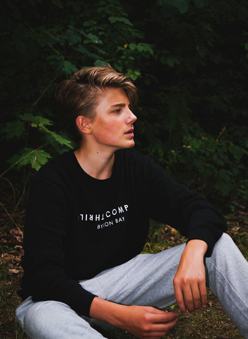 man wearing sweatshirt sitting on ground