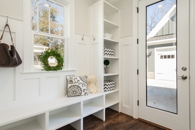 a Clean porch with gray and white floral throw pillow beside rack inside room