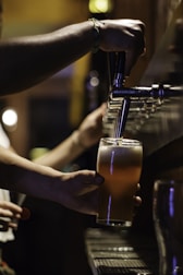 Close-up of a bartender pouring a craft beer into a glass.