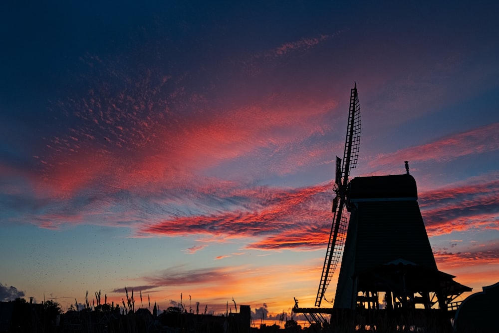 silhouette photograph of windmill under cloudy sky