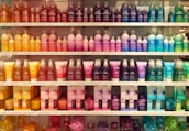 Display of vibrant cosmetics and personal care products on wooden shelves.