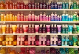 Display of vibrant cosmetics and personal care products on wooden shelves.
