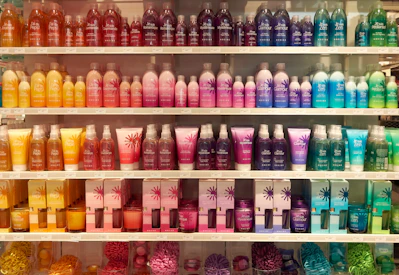 A bright, fresh display of colorful laundry powders and liquid detergents arranged on a wooden shelf.